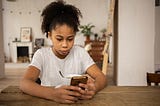 Woman looking down at cell phone with slightly irked expression