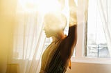 woman dancing in bright sunshine near windows
