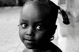 A black-and-white photo of a beautiful black girl looking into your eyes. This depicts how I’d sit my younger self down and share this story if I was told earlier.