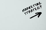 A whiteboard with “marketing strategy” and an arrow written in black ink.