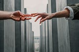 Two hands reaching towards each other against a background of buildings