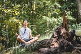 A man meditating in the forest.