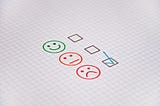 There are three simple faces hand drawn on graph paper. The top one is a smiley face, the second is a straight face, and the third is a frowny face. Beside each face is a check box that a teacher might use in evaluating their students for the day. In this picture, the box beside the frowny face is checked.