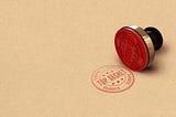 A red “top secret” stamp and stamper on a tan background