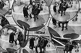 Multiple round convex mirrors showing the same Asian people in a public place.
