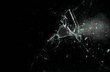 Cracked window with a bullet hole on a black background
