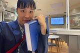 印刷された博士論文を抱える筆者の自撮り。A4サイズ400ページ、青のハードカバーの論文を左手で抱えて右手を伸ばして自撮りした。