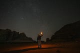 Lady holding a flaming torch in the desert at night