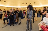 ESD’s Sanyu Tushabe stands in front of a crowd while being honored at the statewide awards for women leaders.