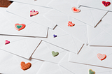 A collection of white envelopes with various colored heart stickers sealing the closures.