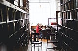 A man sits at a desk in a book shop