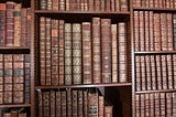 A wall of bookshelves full of old leatherbound books.