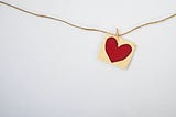 red heart on postcard sized piece of paper hanging from string
