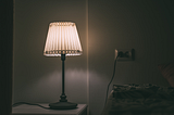 short story — image of bedside lamp in darkened room