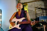 Young woman playing guitar with a blissed out expression.