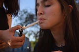 Woman lighting a teenager girl’s cigarette