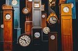 multiple grandfather clocks in various wood colors