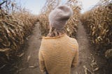 A woman in a cornfield with a choice two paths in front of her.