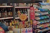 image of the interior of a london corner shop, shelves full of alcohol, sweets and vapes