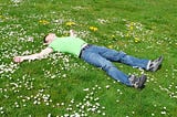 Man lying down relaxing on green grass.