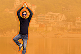 Man doing a tree pose in front of an orange background