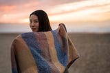 Young woman posing on beach with a blanket