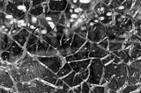 Black and white close-up image of shattered glass