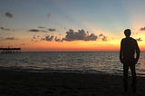 man looking into horizon at the beach