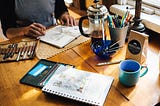 A person doing an sketch on a wooden table