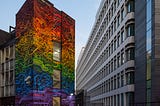 Rainbow colored “Pride Matters” mural on the side of a building in a city