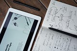 Photo of an ipad and a pen on top of a notebook.