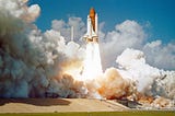 Space shuttle blasting off from Florida with lots of fire and clouds of smoke.