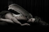 woman with angel wing lying on floor
