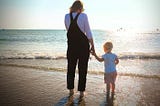 Wife and daughter at the beach looking out to sea