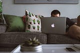 A man on a sofa works on his laptop