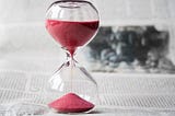 A clear hourglass with red sand.