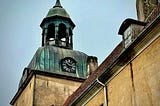 an ancient looking church tower with a clock dial on the side of it