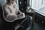 Girl writing in a notebook with coffee next to her