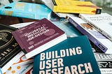 A messy pile of books about UX, including Universal Methods of Design and Building User Research