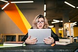 young, frazzled worker at a desk with her laptop