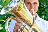 Declan holding his euphonium, light reflected on his face