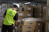 Worker in a warehouse wearing a wearable device on the back of his shirt