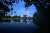 A full moon setting over still water near the Okavango Delta