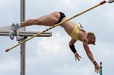 An athlete vaulting over a bar against cloudy background