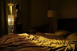 Young Man Standing by Window in Bedroom at Night