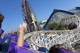 A human hand raised into the air as the human faces an unwinding roller coaster ride.