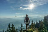 Person standing on the top pf a mountain watching over the hills