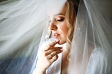 Bride covered with veil contemplates.
