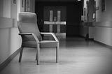 Black & White Picture of a Hospital corridor with a chair in the foreground