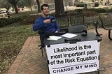 “Change my mind” meme of a man sitting at a table with a sign stating, “Likelihood is the most important part of the Risk Equation — Change my mind.”